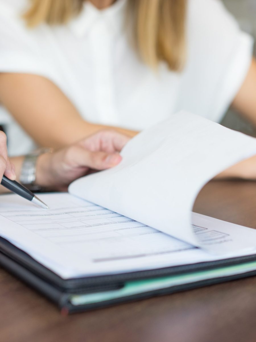 Hands of male executive showing contract to female partner at meeting. Close-up of young Caucasian business colleagues sitting at table and discussing document. Teamwork and partnership concept